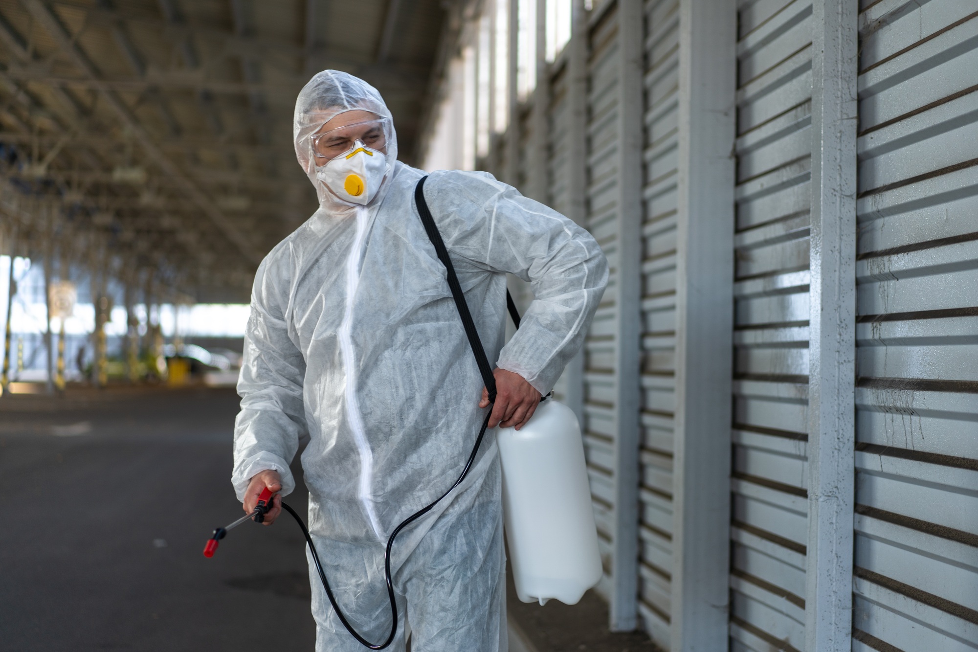 Worker wearing protective suit disinfection gear disinfect surface public place